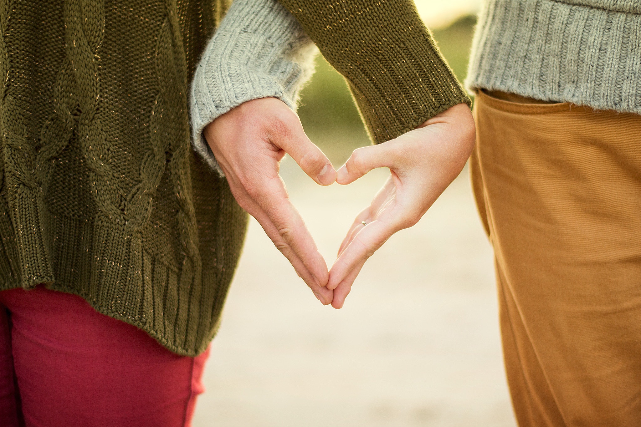 two peoples hands making a heart